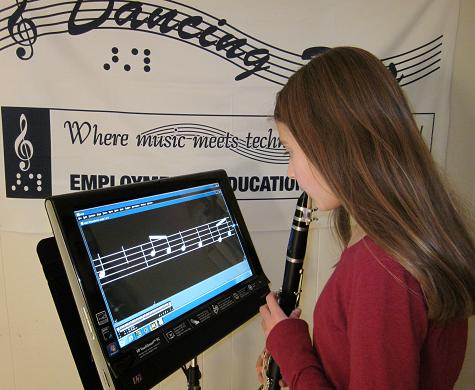 Image of girl holding clarinet standing in front of The Lime Lighter displaying magnified music notation.  Device is mounted on a Manhasset music stand